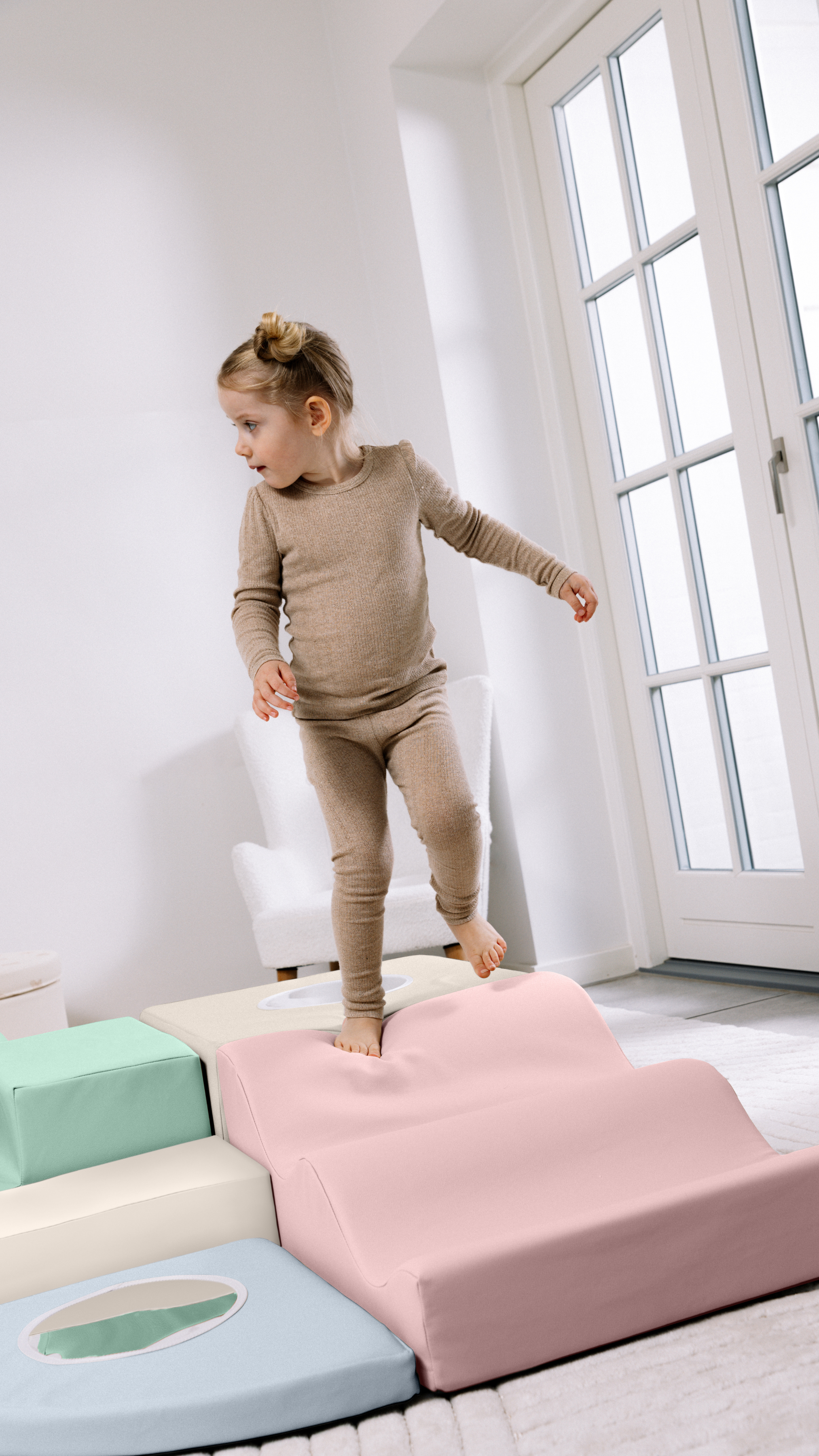 Child standing on a bed with a window in the background