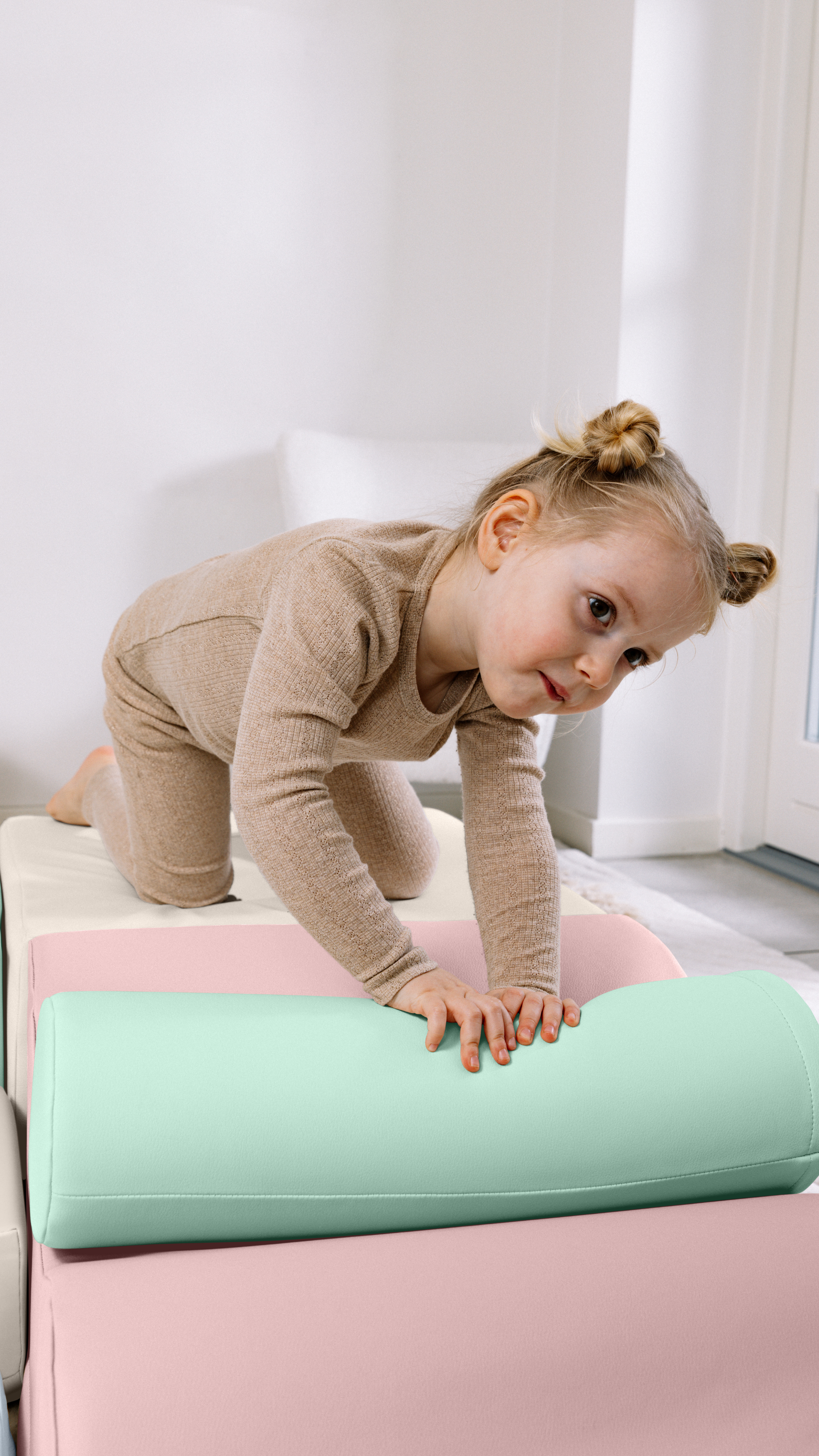 Child playing on a pink and white couch with a green cushion