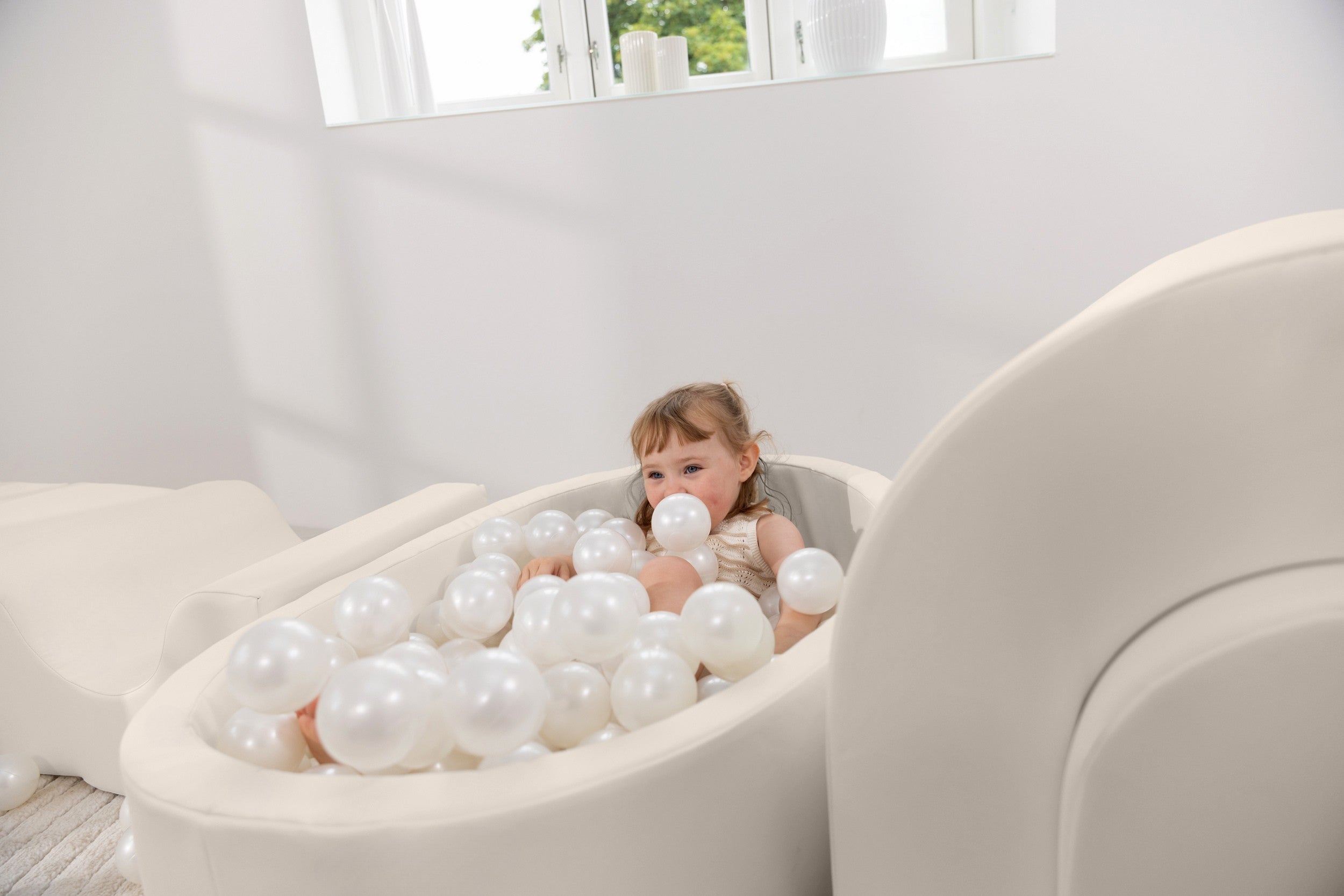 Child playing with balloons in a white room