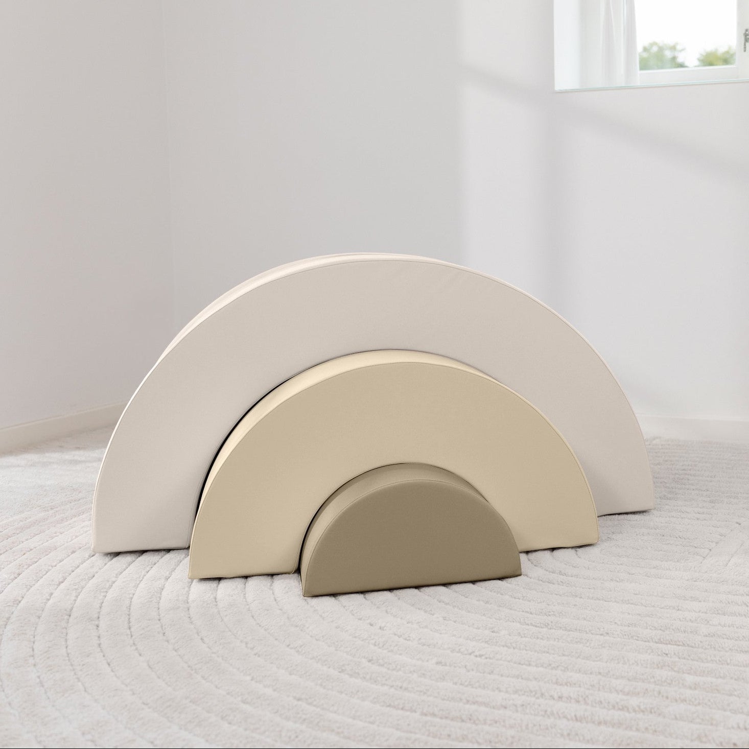 Three beige arch-shaped objects on a textured surface with a window in the background